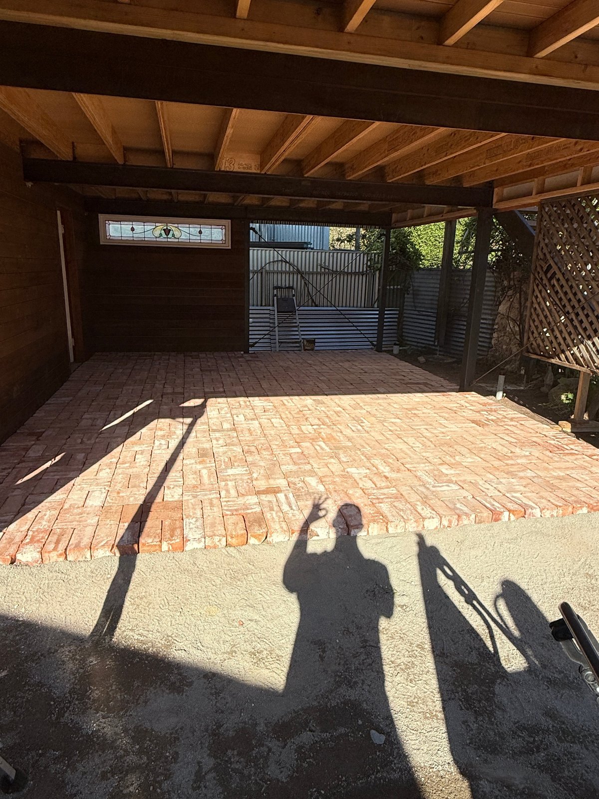 Shadow of person standing in covered outdoor structure with brick floor and wooden beams