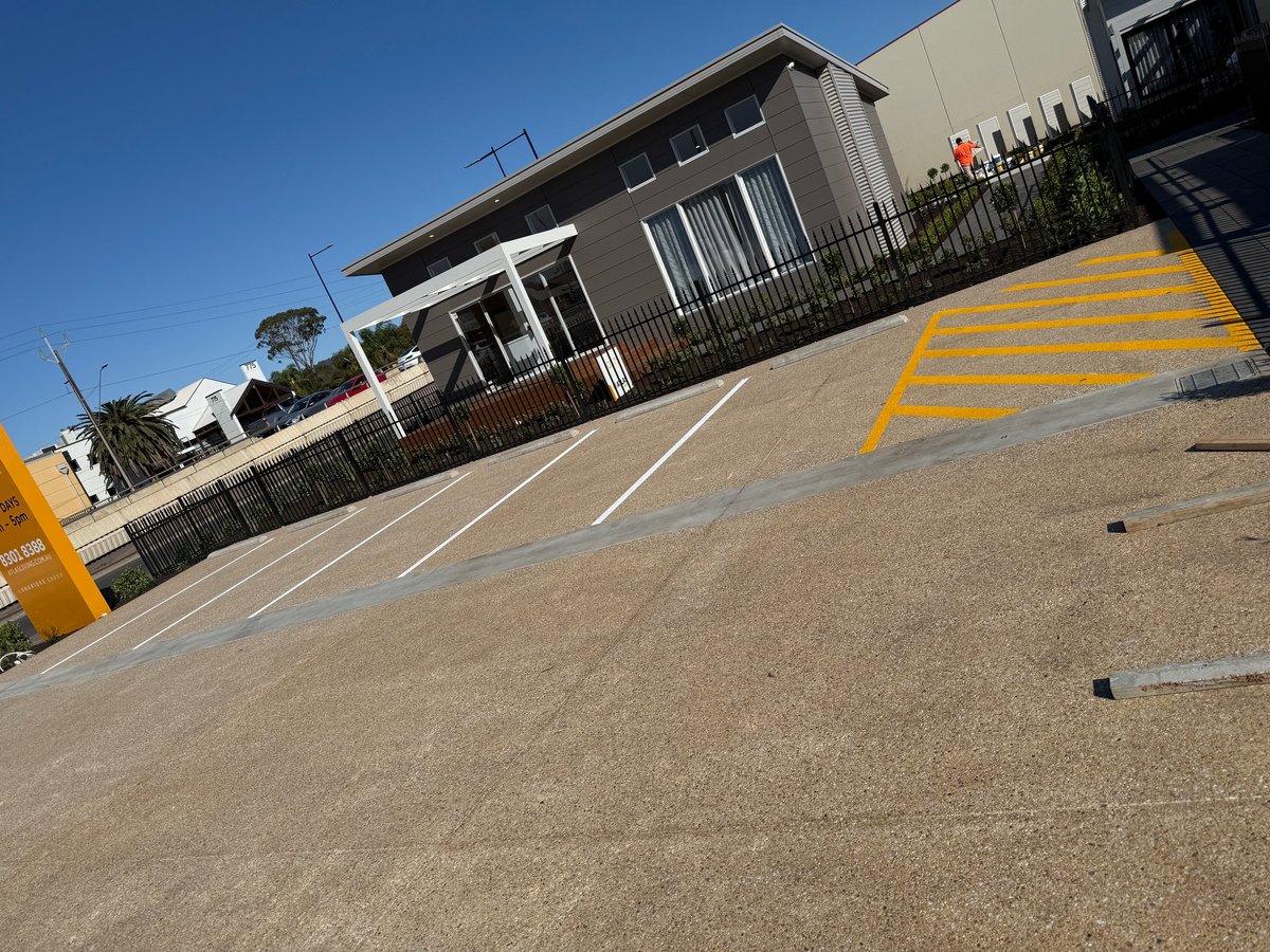 Modern residential home with driveway featuring yellow parking space markings and clear blue sky